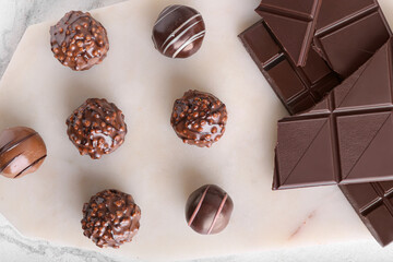 Board with sweet chocolate candies on light background