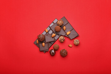Sweet chocolate candies, bar and almonds on color background