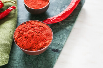 Obraz na płótnie Canvas Bowls with red chili powder on light background