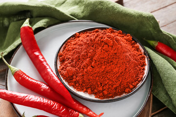 Plate with powder and chili peppers on wooden background