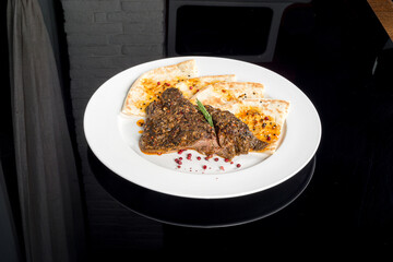 Cooked shoulder of lamb served on a white plate with flatbread