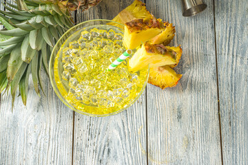 Pineapple margarita cocktail margarita cocktail, Summer alcohol boozy drink with tequila, pineapple juice and slices, white wooden background with tropical palm leaves copy space