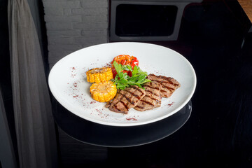 Cooked veal medallions served with corn on a white plate