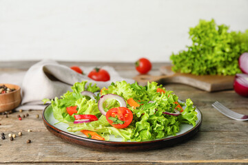 Plate of fresh salad with vegetables on wooden background