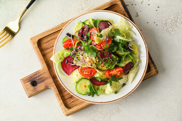 Plate of fresh salad with vegetables on light background