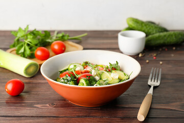 Bowl of fresh salad with vegetables on wooden background