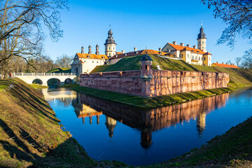 View of historic fortified Nesvizh Castle, landscape park and ponds on sunny winter day, Belarus