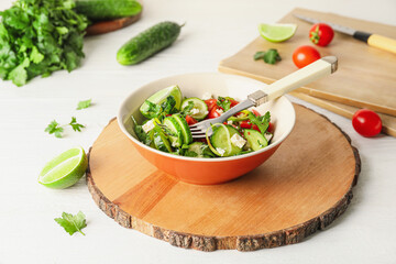 Bowl of fresh salad with vegetables on light wooden background