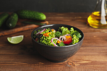 Bowl of fresh salad with vegetables on wooden background
