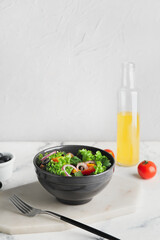 Bowl of fresh salad with vegetables on light background