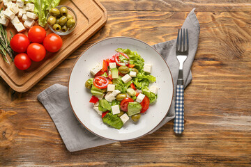 Plate with fresh Greek salad on wooden background