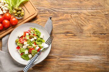 Plate with fresh Greek salad on wooden background