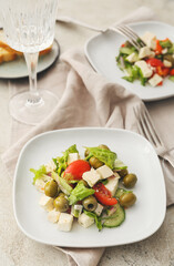 Plates with fresh Greek salad on light background
