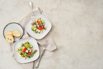 Composition with fresh Greek salad in plates on light background