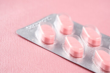 Close up of pink colors pills of blister pack on pink background 