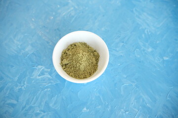 Top view of organic matcha green tea in a bowl and matcha powder. Blue cheerful background.