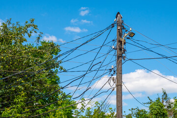 An old wooden electric pole with many wires