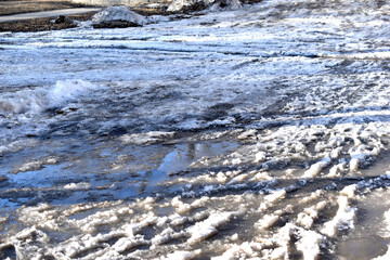 Snow melting in spring on a city street with puddles