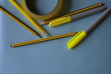 Yellow stationery on blue background. Flat lay with office supplies in yellow shades. School materials