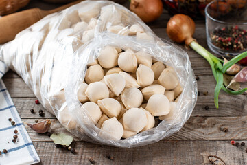 Fototapeta na wymiar Frozen meat dumplings in a plastic bag on wooden table. Semi-finished products