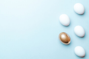 Easter flat. Golden, white colour egg on pastel blue background in Happy Easter decoration. Spring holiday top view concept.