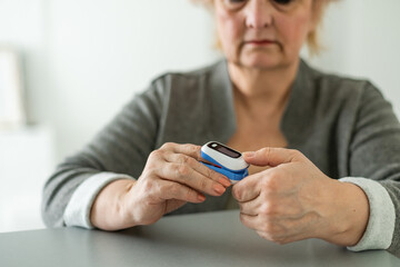 Pulse Oxymeter on a woman finger hand on a wooden table. Top view.