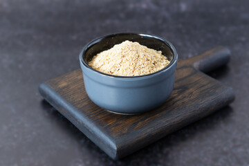 Inactive yeast in a bowl on a dark wooden board. Healthy food concept.