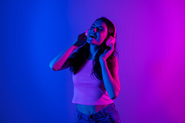 Photo of young lovely charming smiling girl listening music headphones enjoying party isolated on neon blue background