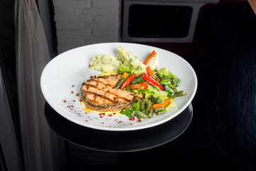 Fish steak served with vegetables on a white plate