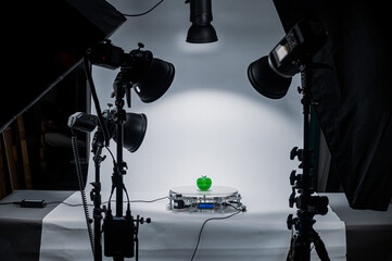 A rotating table for subject photography, with a plastic green apple on it, on a table in a photo...