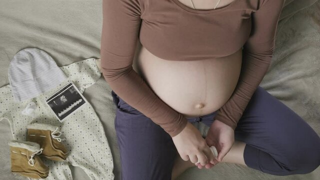 expecting pregnant woman with big belly sitting on couch at home, taking pills