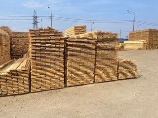 Wooden boards are stored outdoors. Wooden boards, lumber, industrial wood, timber. Pine wood timber...