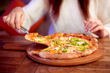 woman Hand takes a slice of sliced Pizza with Mozzarella cheese, tomatoes, pepper, olive. Italian pizza Margherita or Margarita on wooden table background