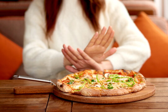 losing weight woman refuses baking and fatty foods. hand gesture I not eat pizza. woman on diet or proper nutrition.