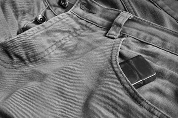 Metal lighter in the front pocket of men's jeans. Black and white fashion photography.