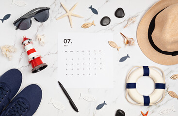 Flat lay with calendar for July with summer holidays fashion accessories. Social media blog, schedule, planning, summer vacations concept. Flatlay, top view