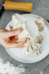 the hand holds the chikali by the tail. Khinkali in a Georgian restaurant in hand. Georgian cuisine
