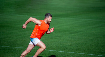 energetic athletic muscular man runner running outdoor on green grass, copy space, success