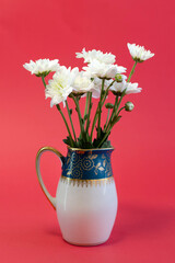 Fresh white flowers in green milk jug on light wooden background close up