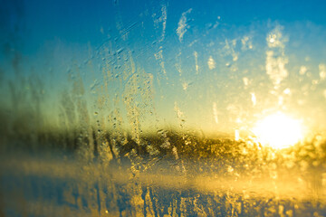  frost over the sun on frozen  window at sunset.
