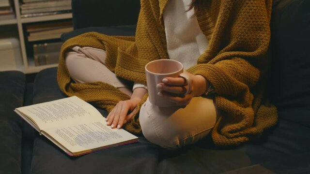 woman reading book and drinking tea at home	