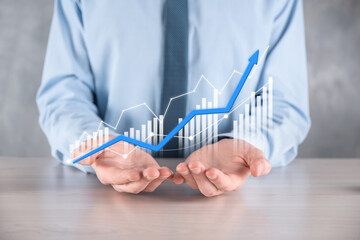 Businessman man holding a graph with positive profits growth. plan graph growth and increase of chart positive indicators in his business.more profitable and growing