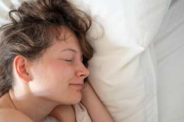 Young caucasian woman sleeping in bed. Cosy pillow and sleeping woman. Dream and relax concept