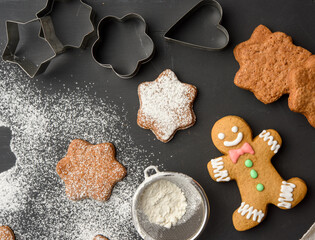 Star shaped baked gingerbread cookies sprinkled with powdered sugar on a black table