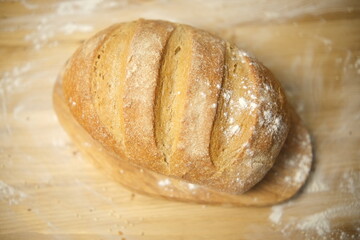 Bread freshly baked on a wooden table. Flour, bakery. The cooking process is captured in 4k resolution. Selective focus. Round loaf