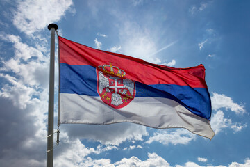 Serbian flag waving against blue cloudy sky