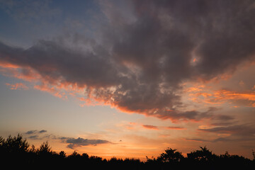 The sky at sunset before bad weather. Low red sunlight illuminates thunderclouds.