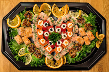 Big sushi set with green salad and orange