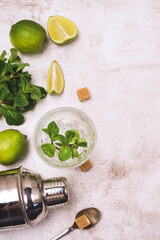 Ingredients for Making Mojitos Gass with Ice Cube Fresh Mint Leaves Sugar and Ripe Lime Cocktail Shaker on Concrete Background Top View Copy Space Vertical