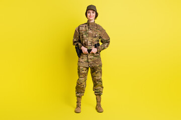Full length portrait of charming satisfied girl standing hands hold tactical belt isolated on yellow color background